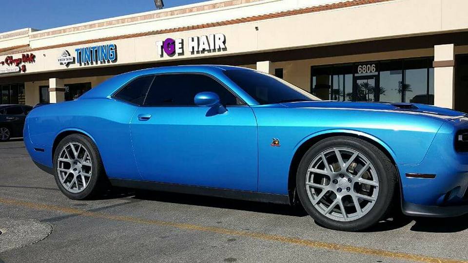 Blue Dodge Challenger with tinted windows parked in front of the shop