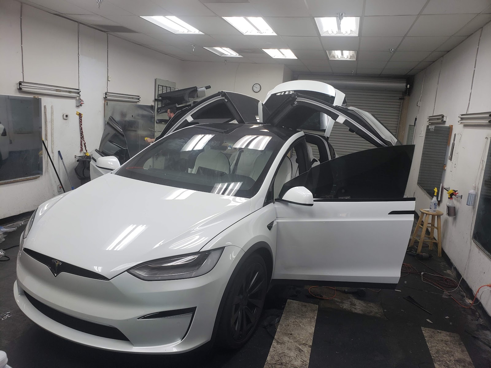 White Tesla Model X with doors open being tinted inside the shop