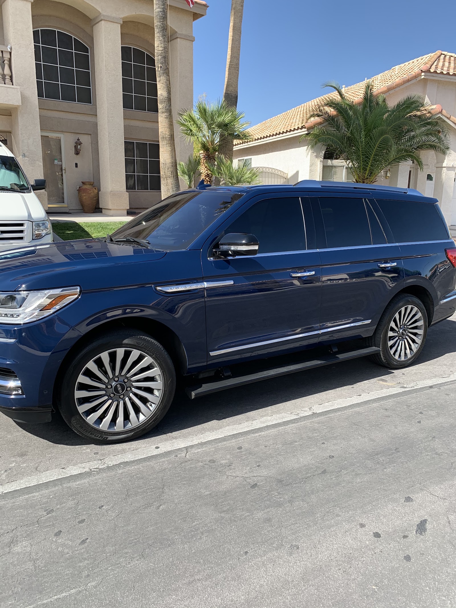Blue Lincoln Navigator SUV with tinted windows parked in front of a home